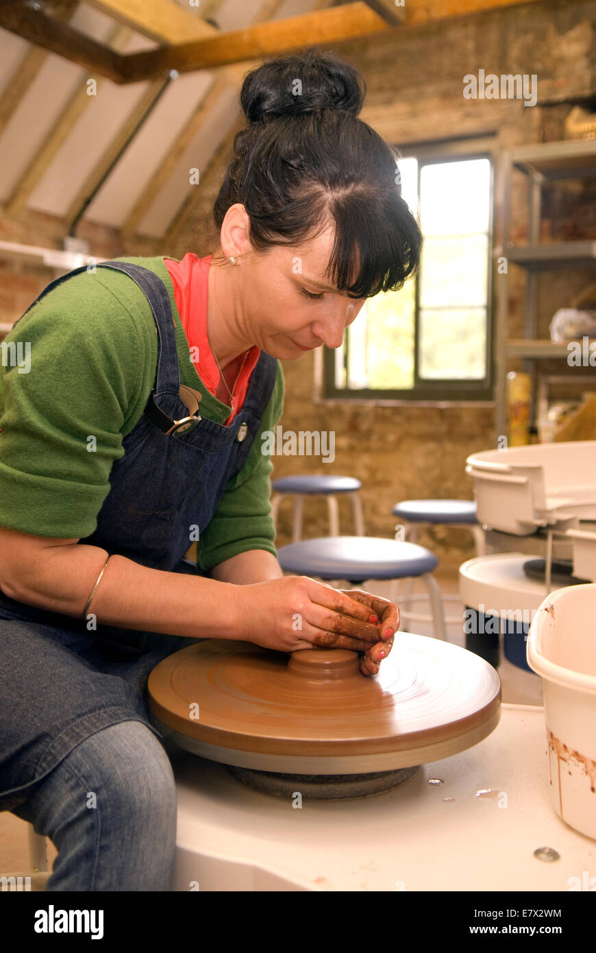 Woman demonstrating claybowl making on the throwing wheel at a heritage and demonstration day at a local pottery, Farnham, UK. Stock Photo