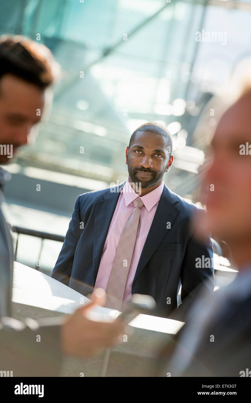 A business man seated smiling confidently, in a group with two others. Stock Photo