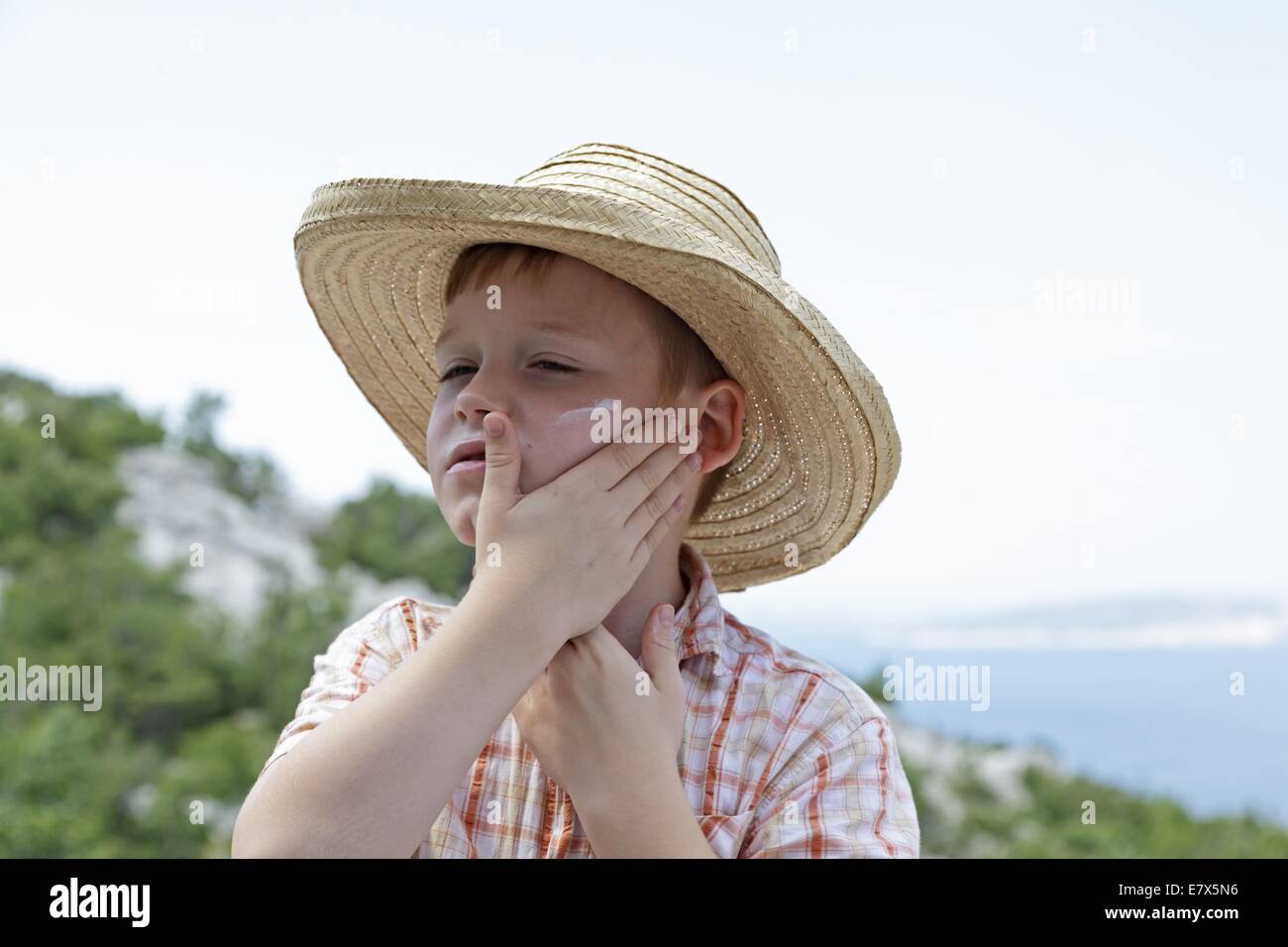 Boy in cozy beige clothes applying sunscreen protection creme on his face.  Sun protection during summer sea vacation. Children healthcare at travel t  Stock Photo - Alamy