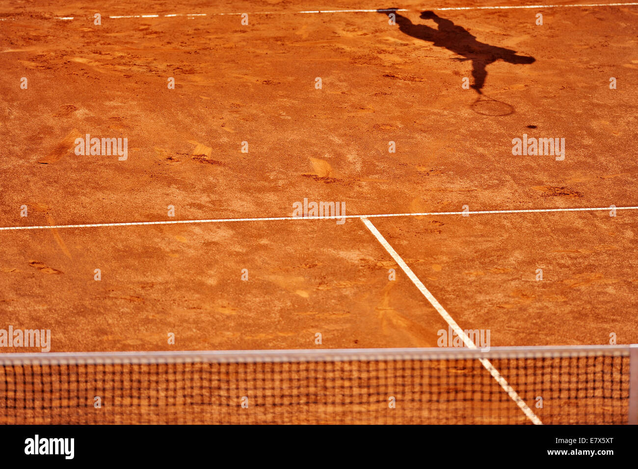 Shadow of a tennis player serving on a clay court Stock Photo