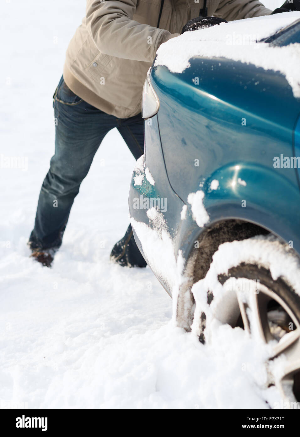 closeup of man pushing car stuck in snow Stock Photo