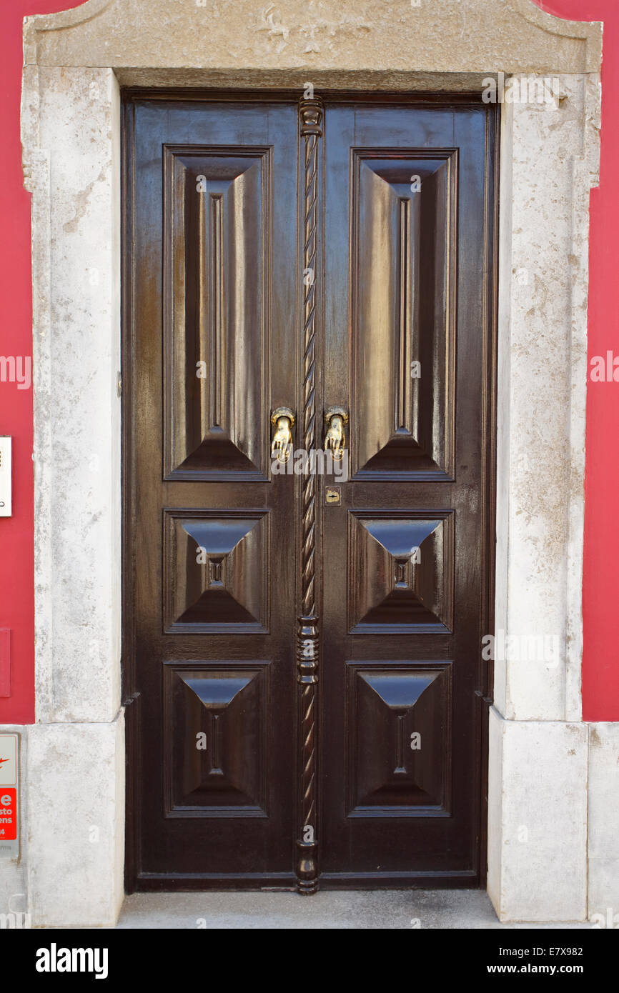 Brown door in the old town of Tavira have little brass door handles in the shape of hands. Stock Photo