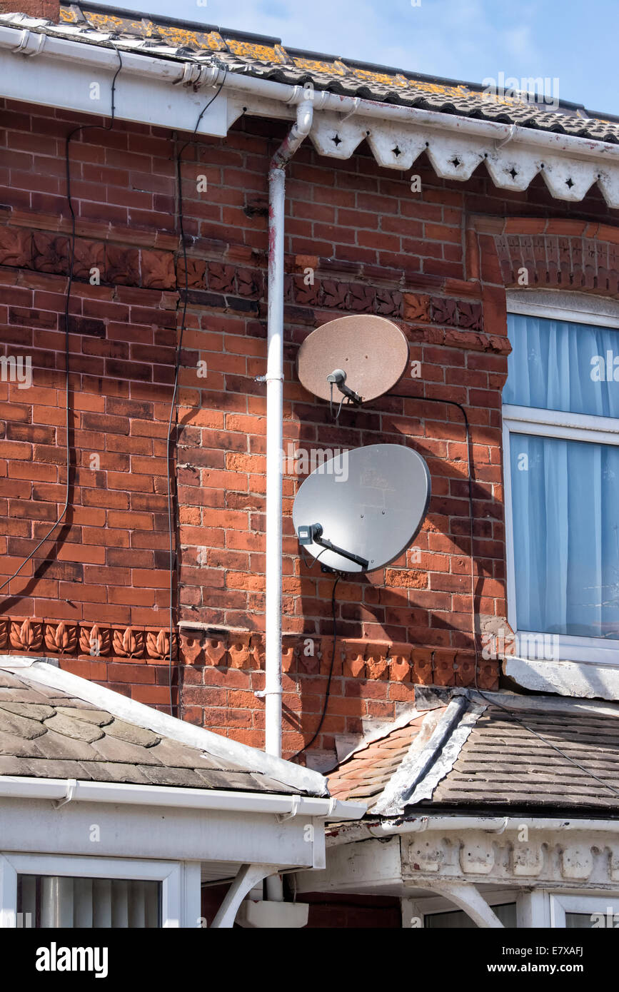 Two SKY TV  Satellite dishes (one very rusty) attached to a suburban house Stock Photo