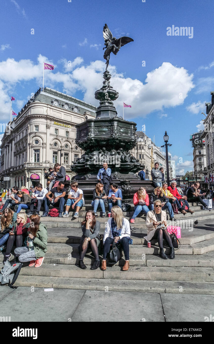Piccadilly Circus,London, Tourists sit on the Steps of the Eros Statue Stock Photo