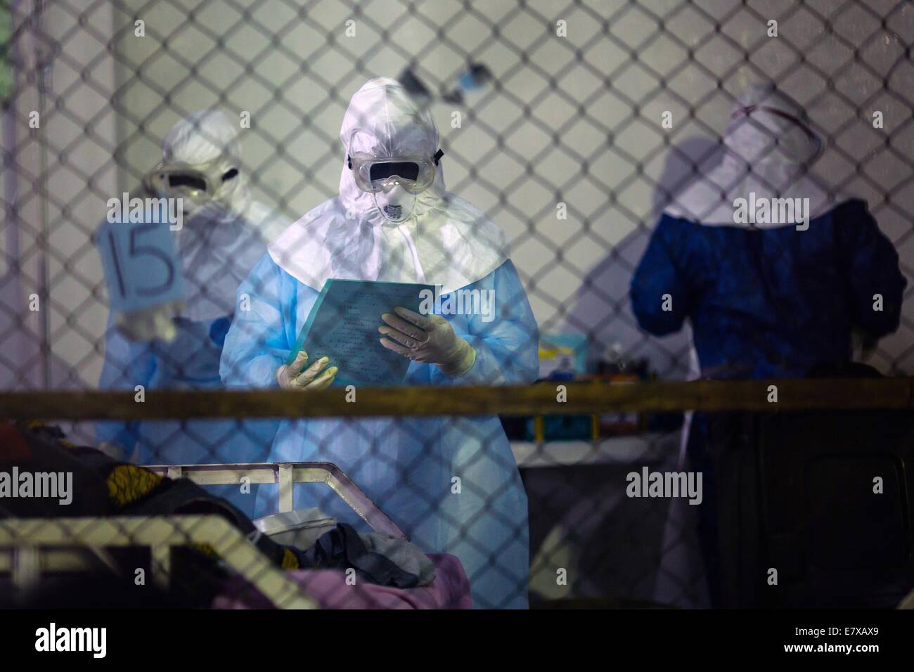 A health care worker checks on patients admitted to the Ebola Treatment Unit at the newly opened Island Clinic September 22, 2014 in Monrovia, Liberia. The facility opened by the WHO and the Ministry of Health in response to the surge of patients needing an Ebola Treatment. Stock Photo