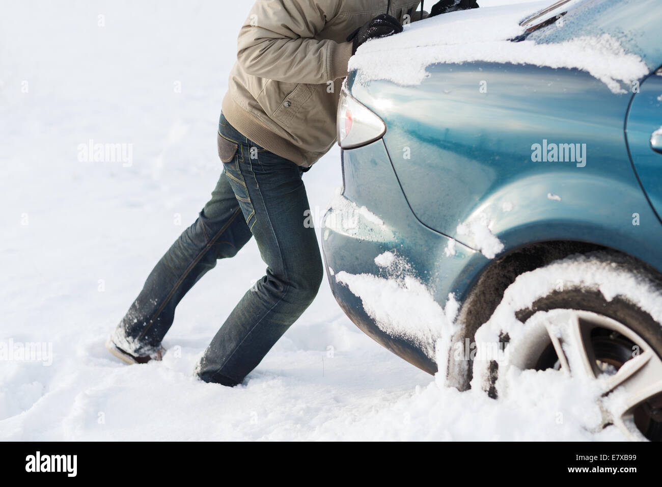 closeup of man pushing car stuck in snow Stock Photo