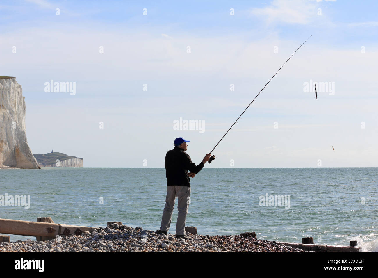 Cuckmere Haven, East Sussex, England. 25th September 2014. A fisherman casts his line into the sea from the beach in front of the towering chalk cliffs known as the Seven Sisters. Credit:  Julia Gavin UK/Alamy Live News Stock Photo