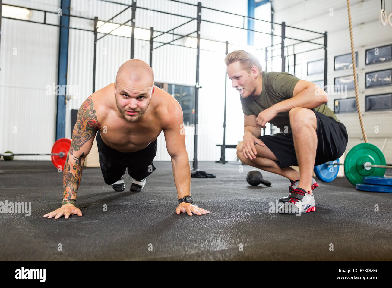 Trainer Assisting Man In Doing Pushups Stock Photo