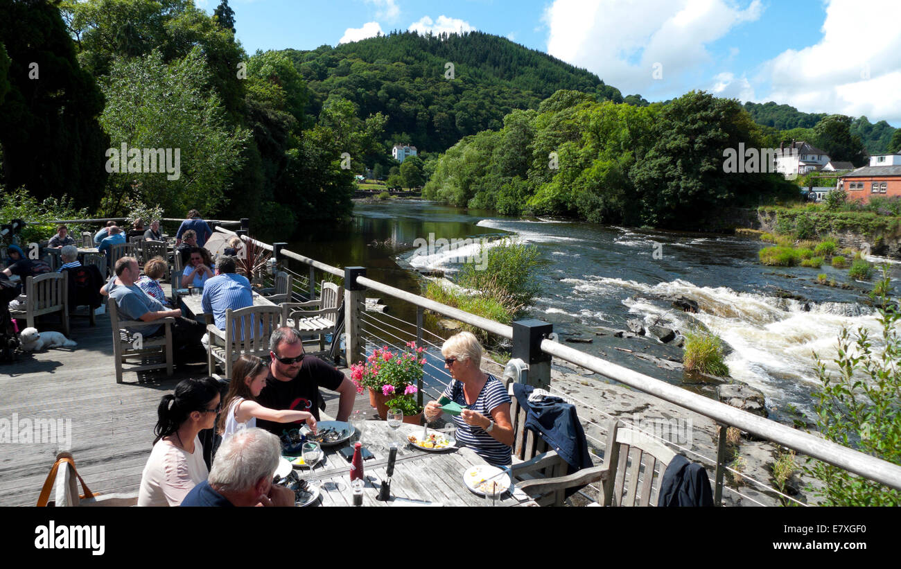 People eating alfresco at the Corn Mill restaurant on the River Dee in summer Llangollen Denbighshire North Wales KATHY DEWITT Stock Photo
