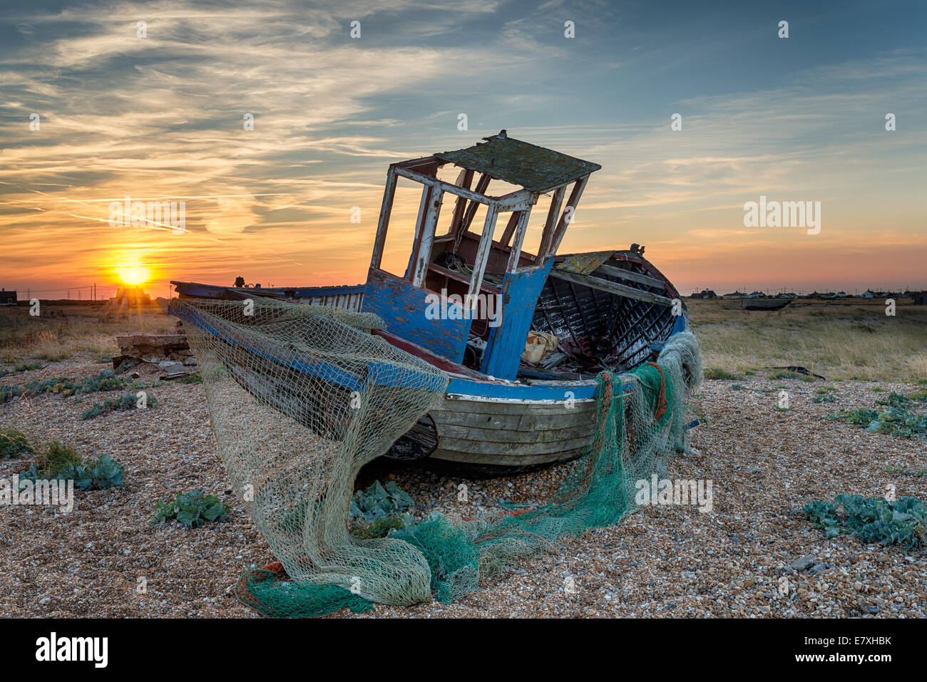 An old abandoned wooden fishing boat with nets washed up on a shingle ...