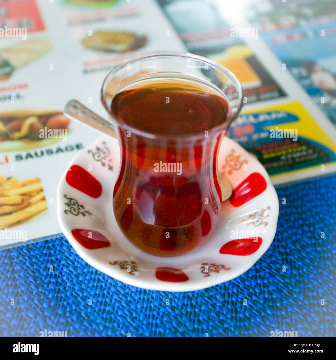 A turkish tea in cup with saucer sitting on a menu and blue table cloth Stock Photo