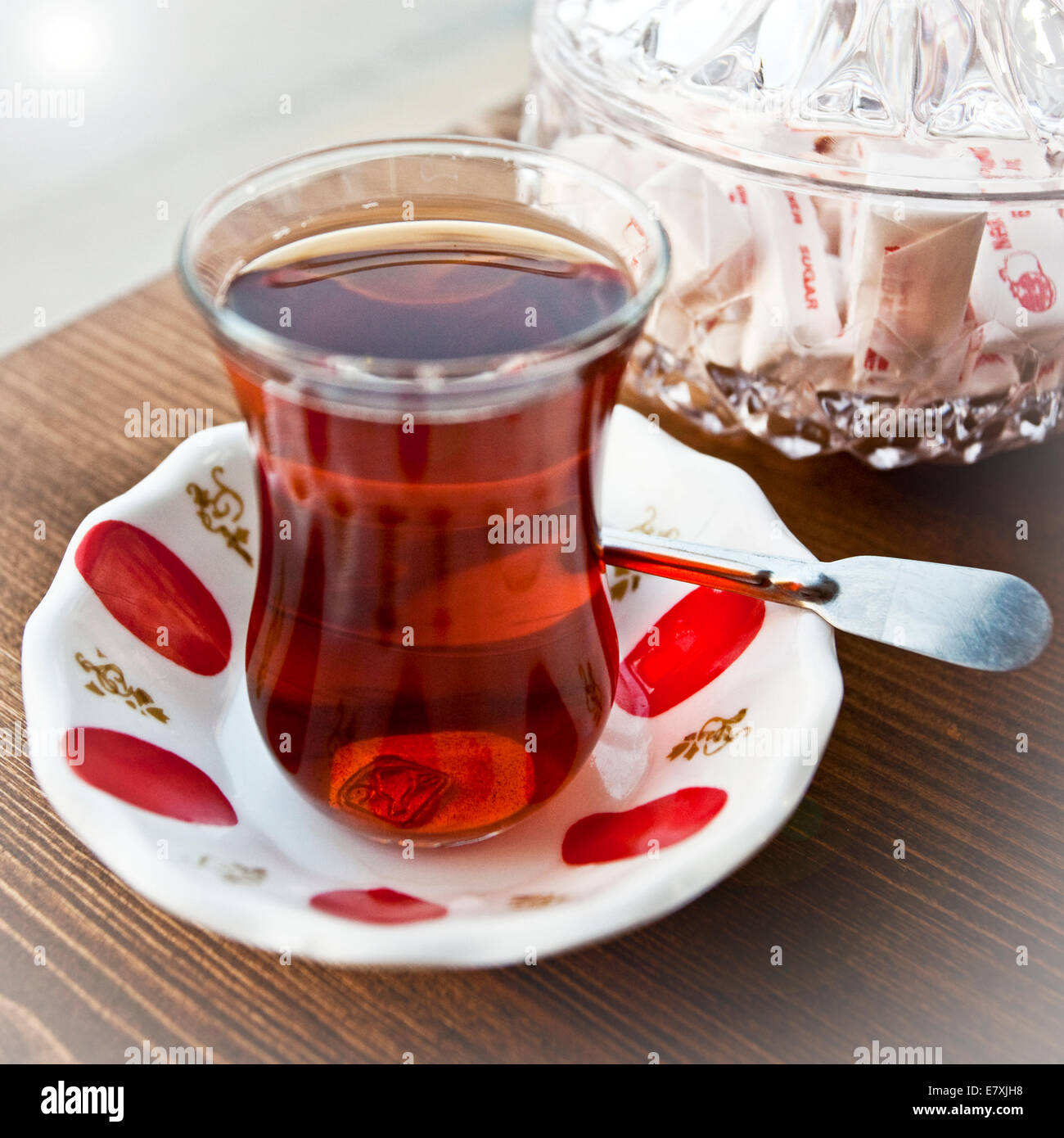 Turkish tea on saucer with spoon and sugar packets in background Stock Photo