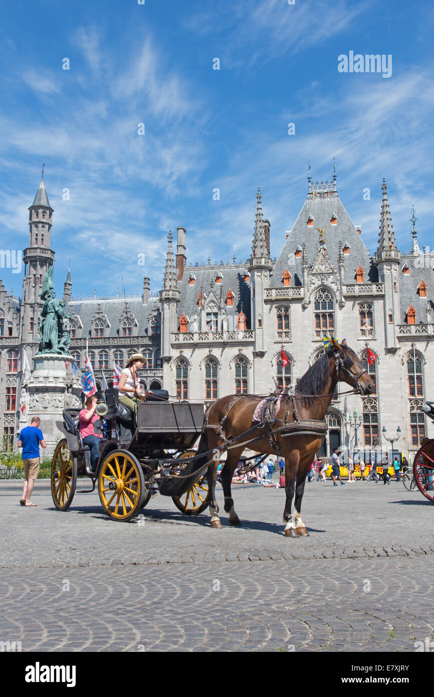 BRUGES, BELGIUM - JUNE 13, 2014: The Carriage on the Grote Markt and the Provinciaal Hof building in background. Stock Photo