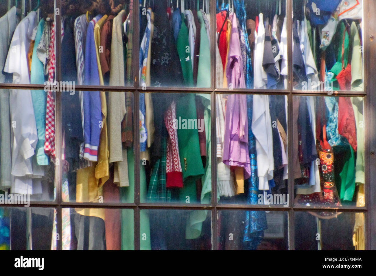 Used clothing on hangers displayed in a thrift store window Stock Photo