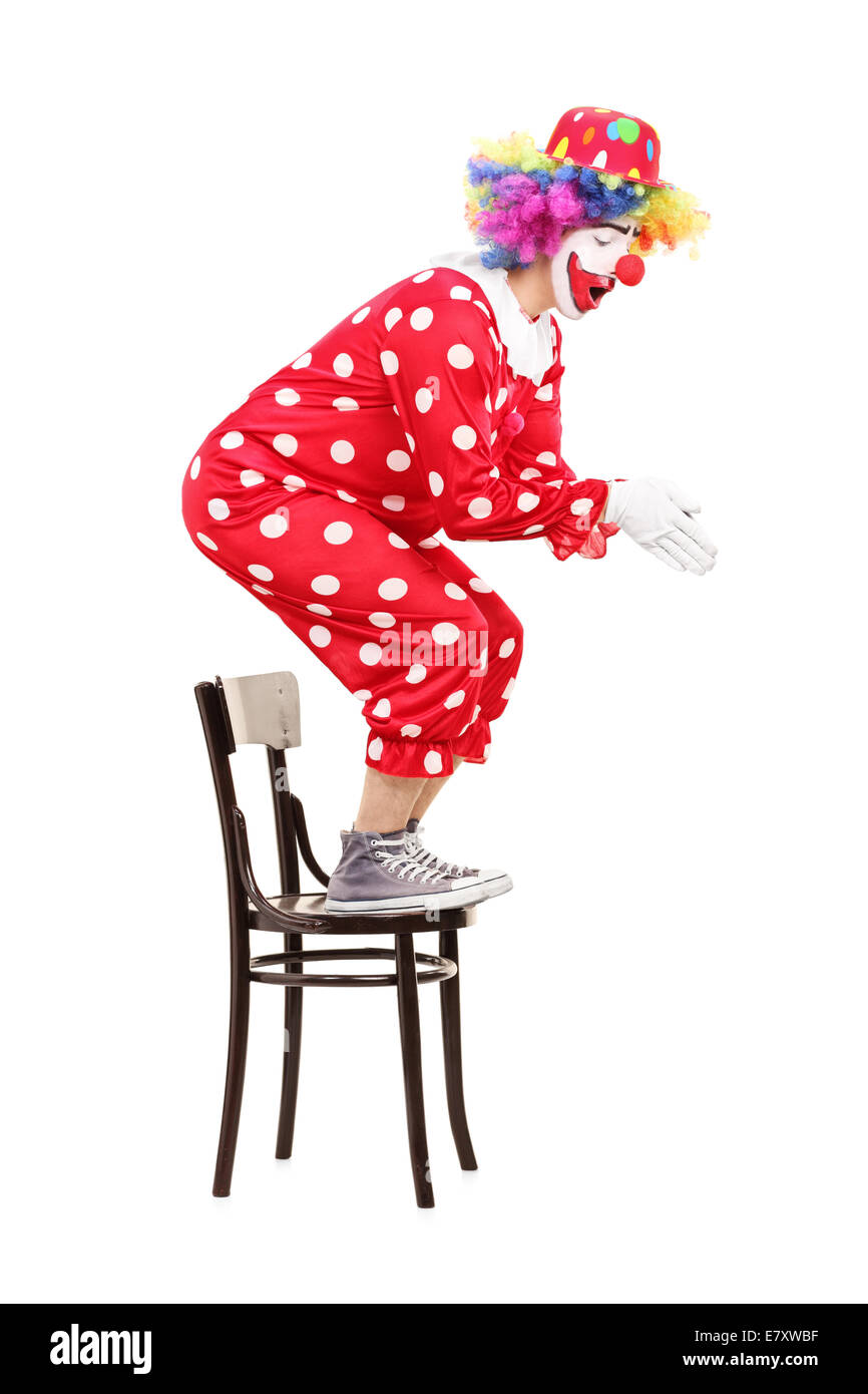 Male clown preparing to jump off a chair isolated on white background Stock Photo