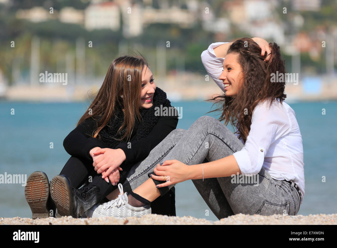 Two girlfriends, teenagers, sitting on the beach, Menton, Alpes ...