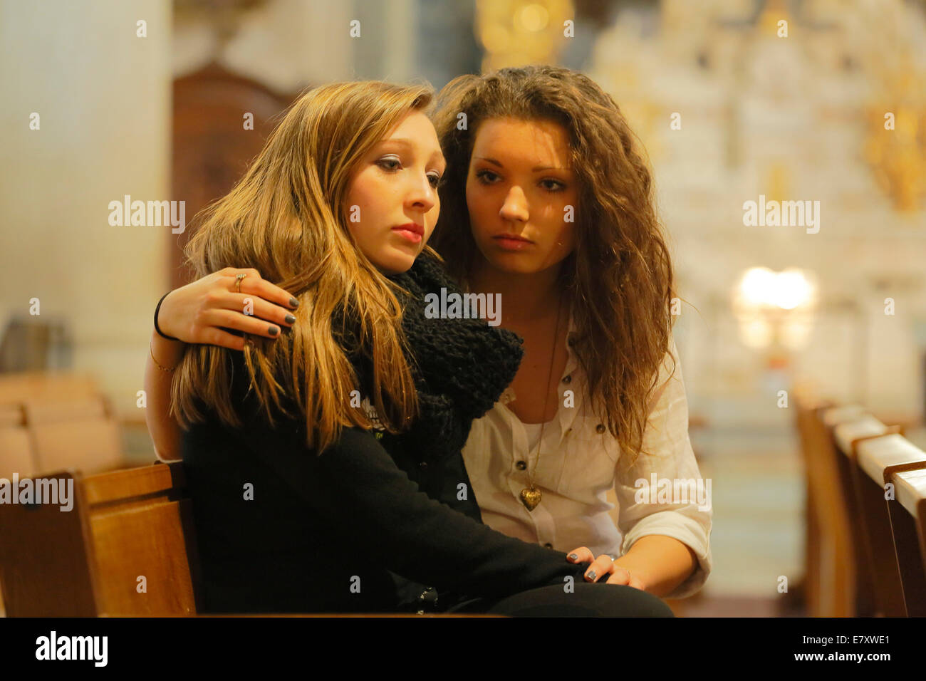 Two girlfriends, teenagers, sitting in a church, one embracing the other, Menton, Alpes-Maritimes, Provence-Alpes-Côte d'Azur Stock Photo