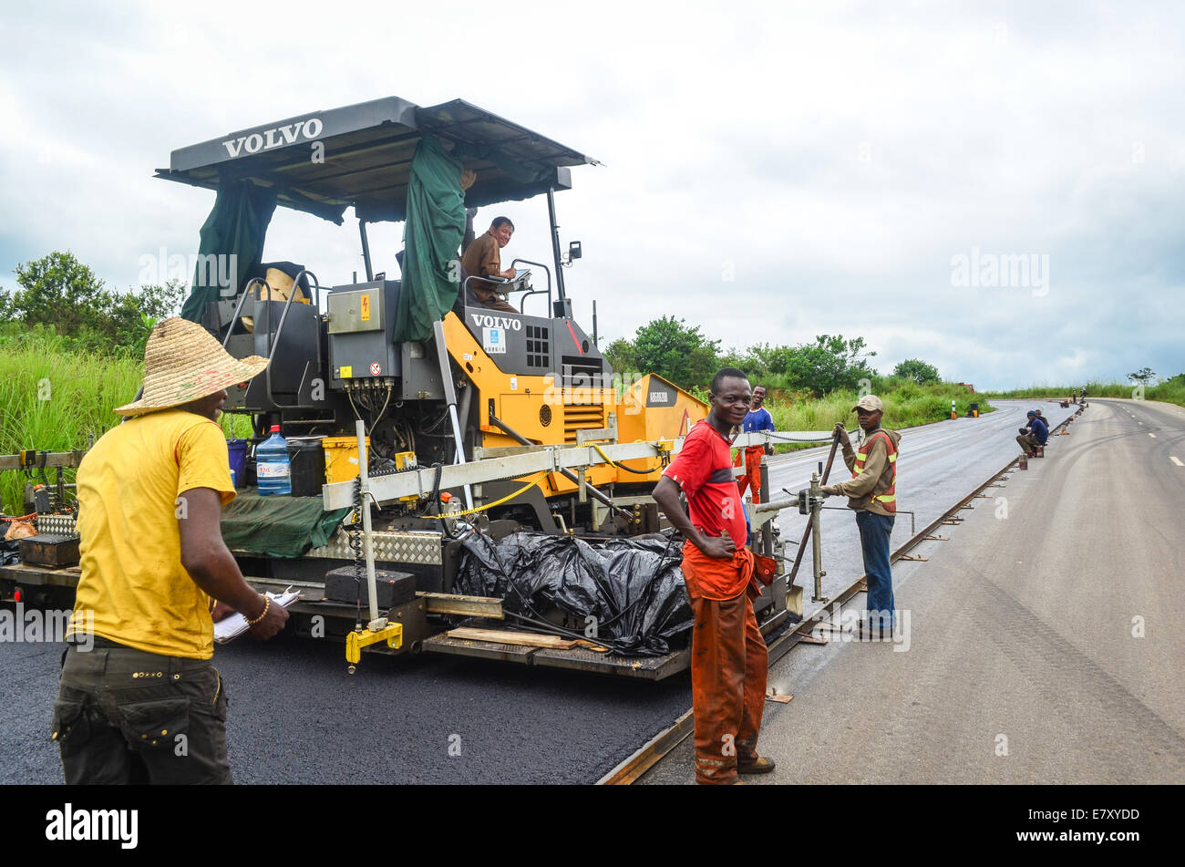 Chinese and Congolese men laying down a new layer of asphalt on the construction of the road Pointe-Noire / Dolisie in Congo Stock Photo