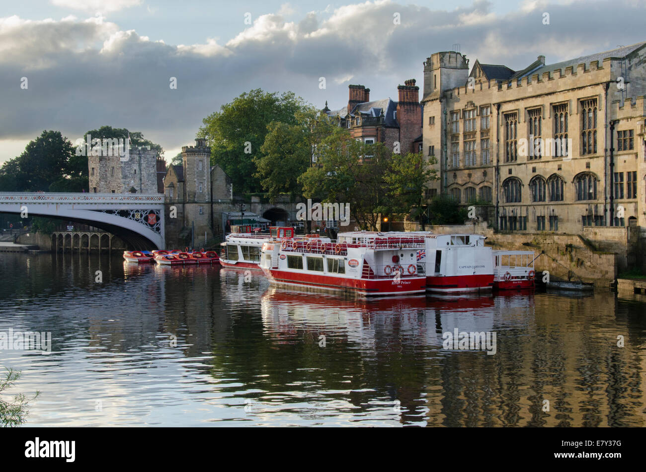 City cruise boats moored in summer evening sun by Guildhall & Lendal Bridge - view from south bank of River Ouse, York, North Yorkshire, England, UK. Stock Photo