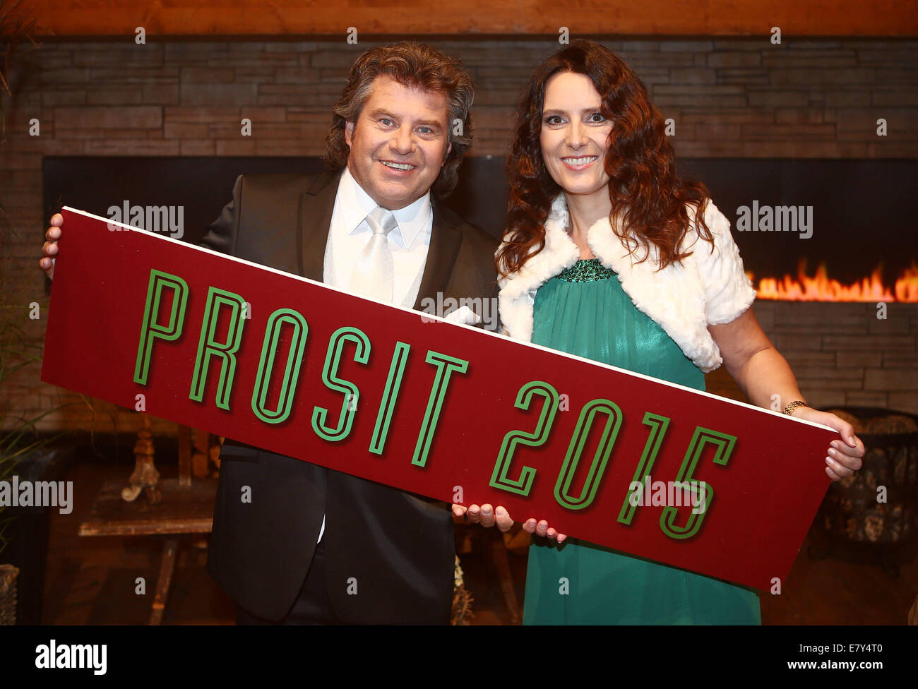 Presenter of the German television music show 'Musikantenstadl', Andy Borg (L) and his wife Birgit hold a sign in their hands which reads 'Prosit 2015' (cheers 2015), as they pose for a  photo shooting during a show rehearsal in Passau, Germany, 25 September 2014. Photo: Bodo Schackow/dpa - NO WIRE SERVICE - Stock Photo