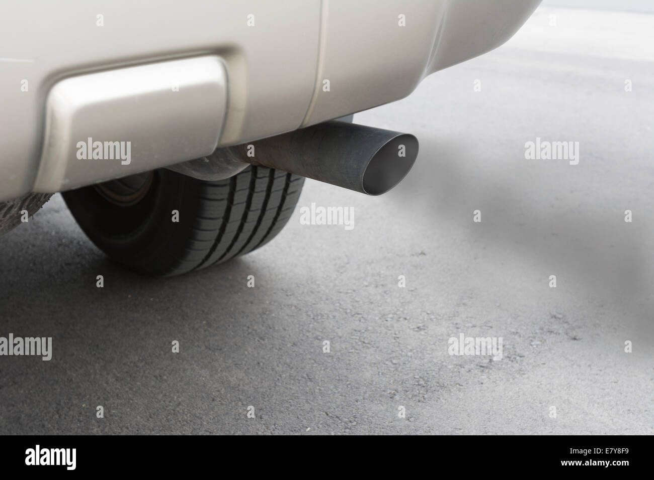 A car emits carbon monoxide gas from its exhaust tailpipe, showing how pollution is formed. Stock Photo