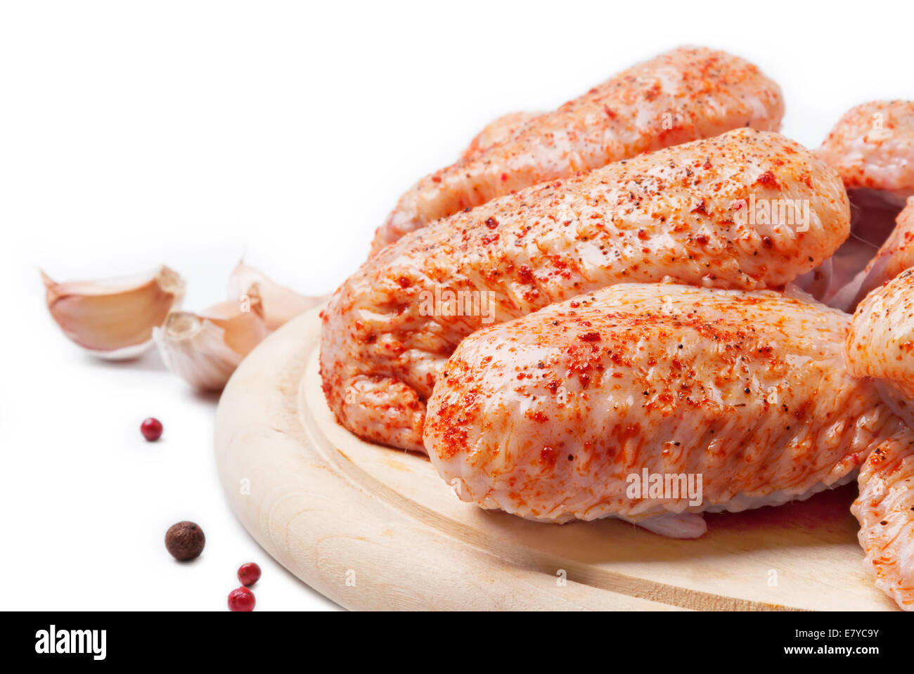 Spicy raw chicken wings on a wooden  board with pepper and garlic Stock Photo