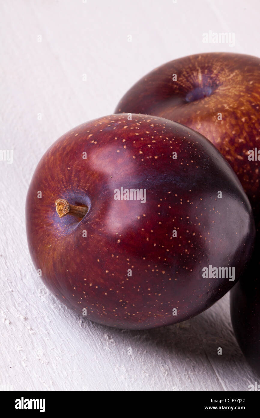 Fresh ripe red juicy appetizing plum close up view with the stalk facing the camera in a concept of healthy eating and diet with Stock Photo