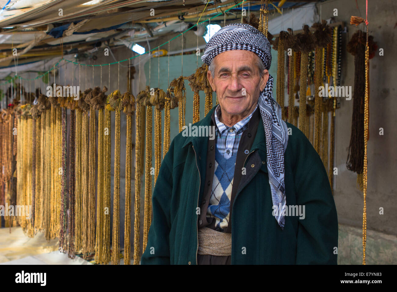 A Kurdish shopkeeper wearing traditional clothing selling prayer chains in Erbil (Arbil), Iraqi Kurdistan province, Iraq. Stock Photo