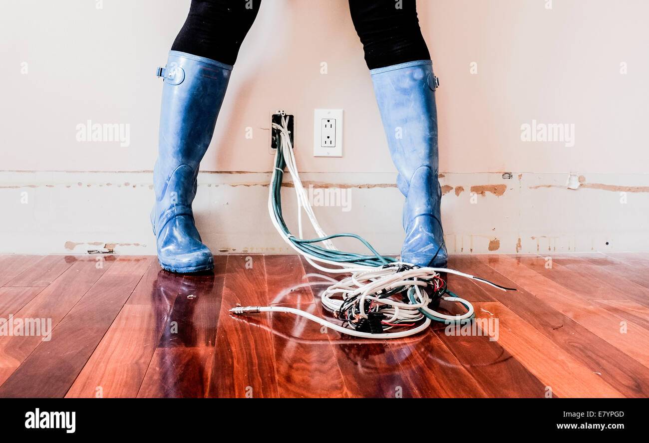 Woman wearing galoshes standing above electrical wiring Stock Photo