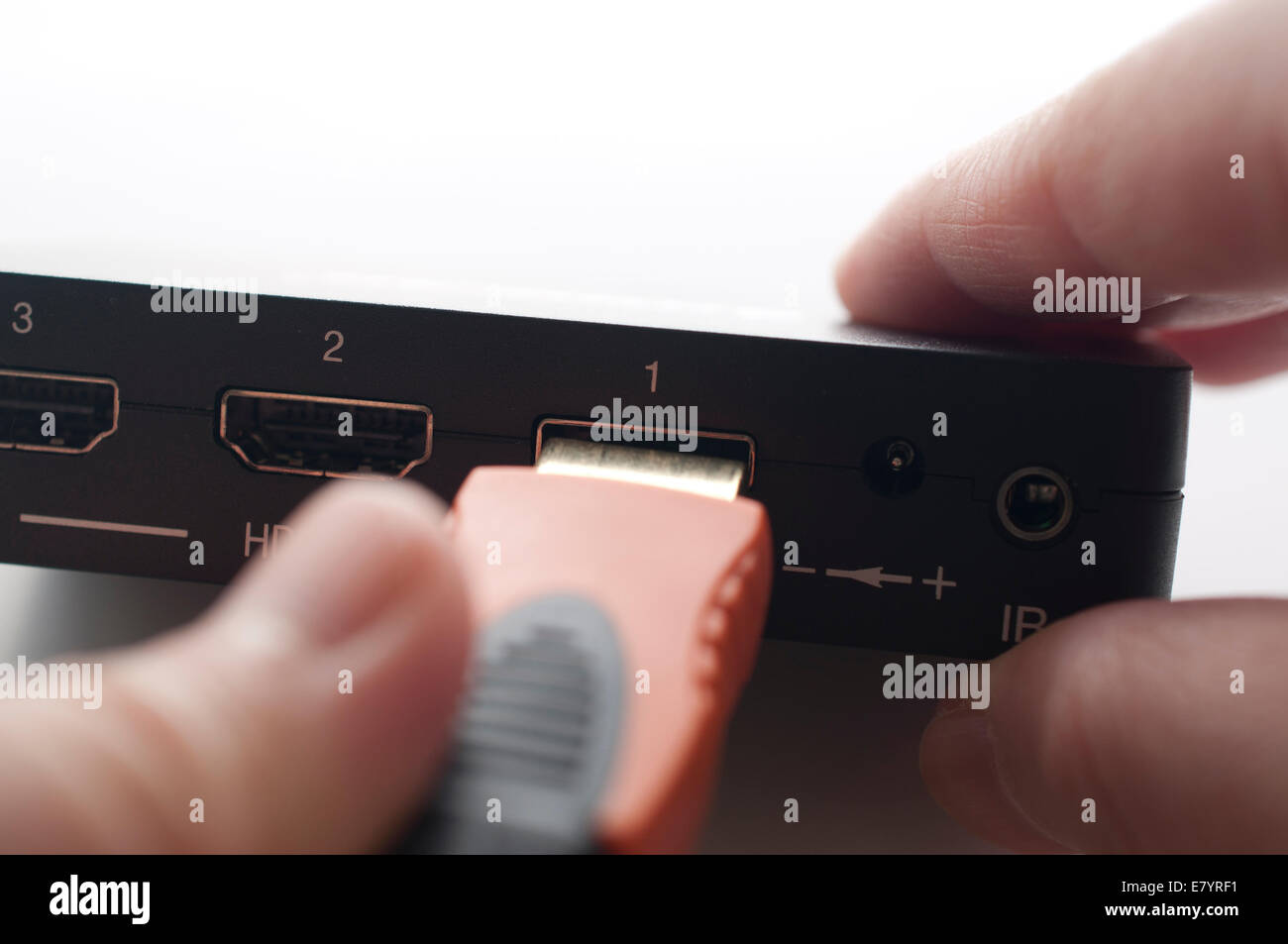 Hand holding hdmi cable to plug in of device Stock Photo