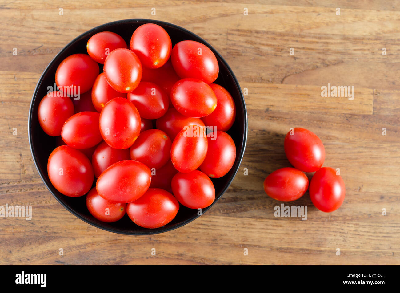 cherry tomatoes in a black bowl on aged wooden table Stock Photo - Alamy