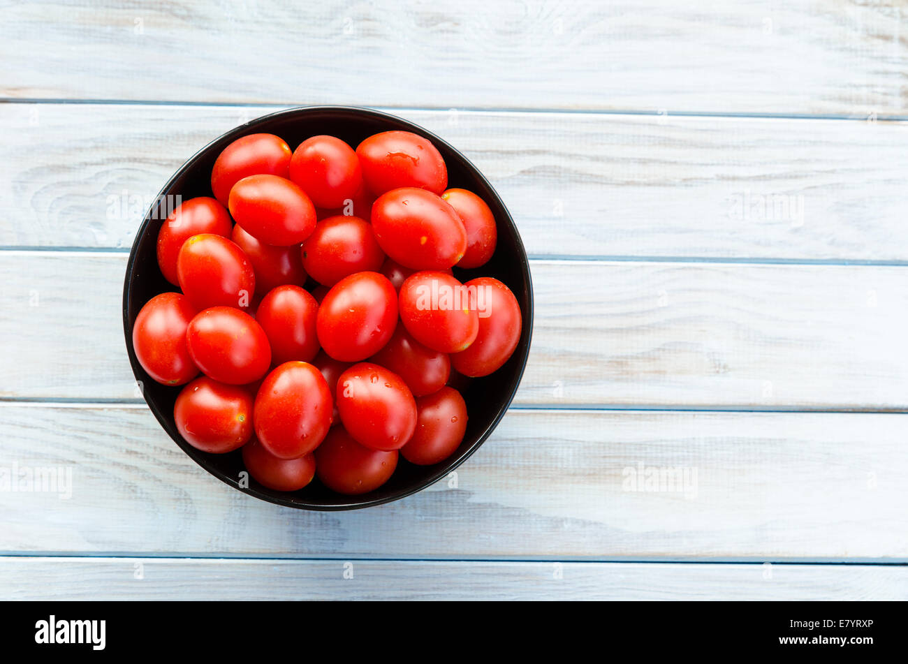 cherry tomatoes in a black bowl on aged wooden table Stock Photo - Alamy