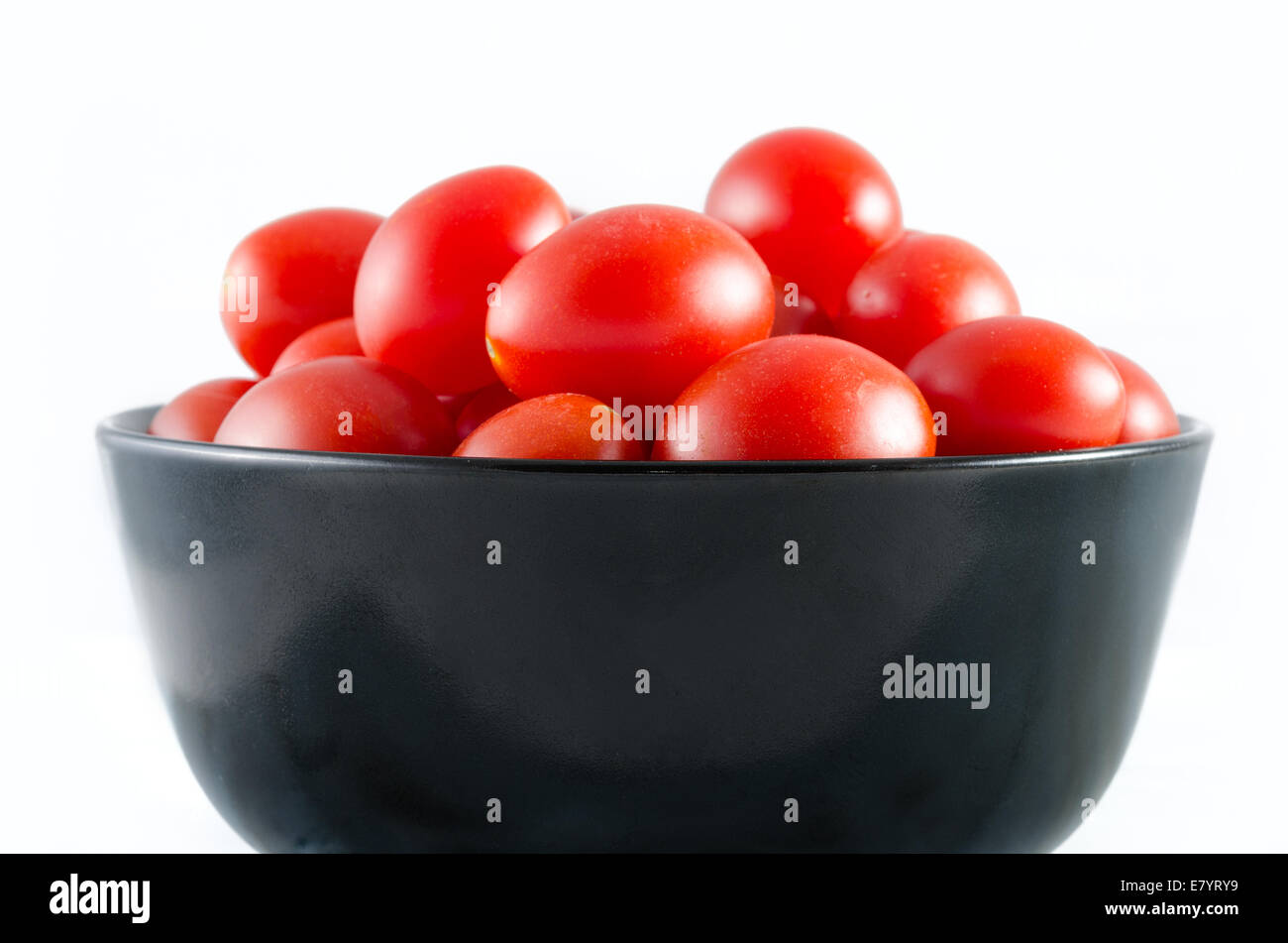 cherry tomatoes in a black bowl isolated on white Stock Photo - Alamy