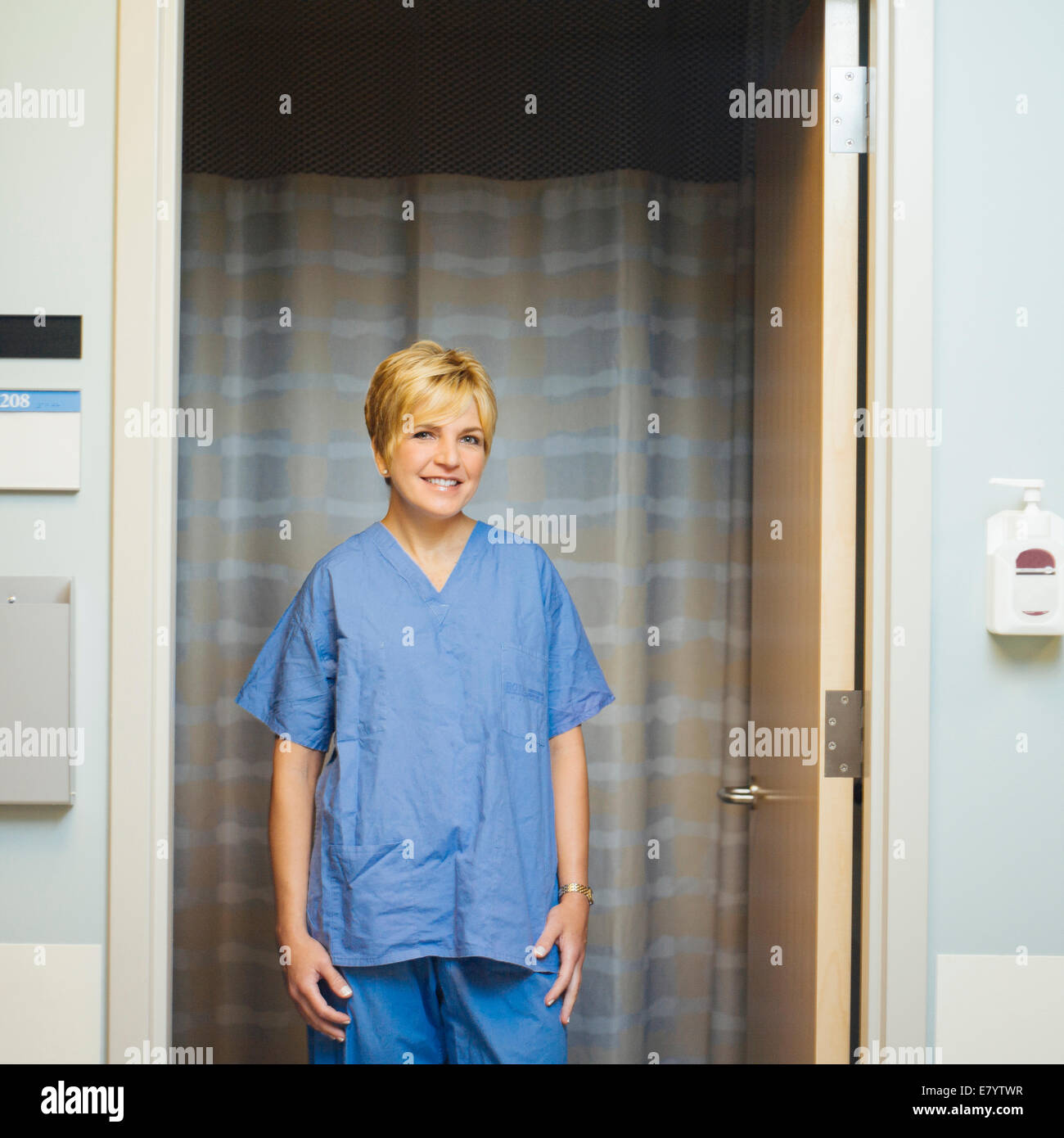 Doctor in scrubs standing in doorway, smiling Stock Photo