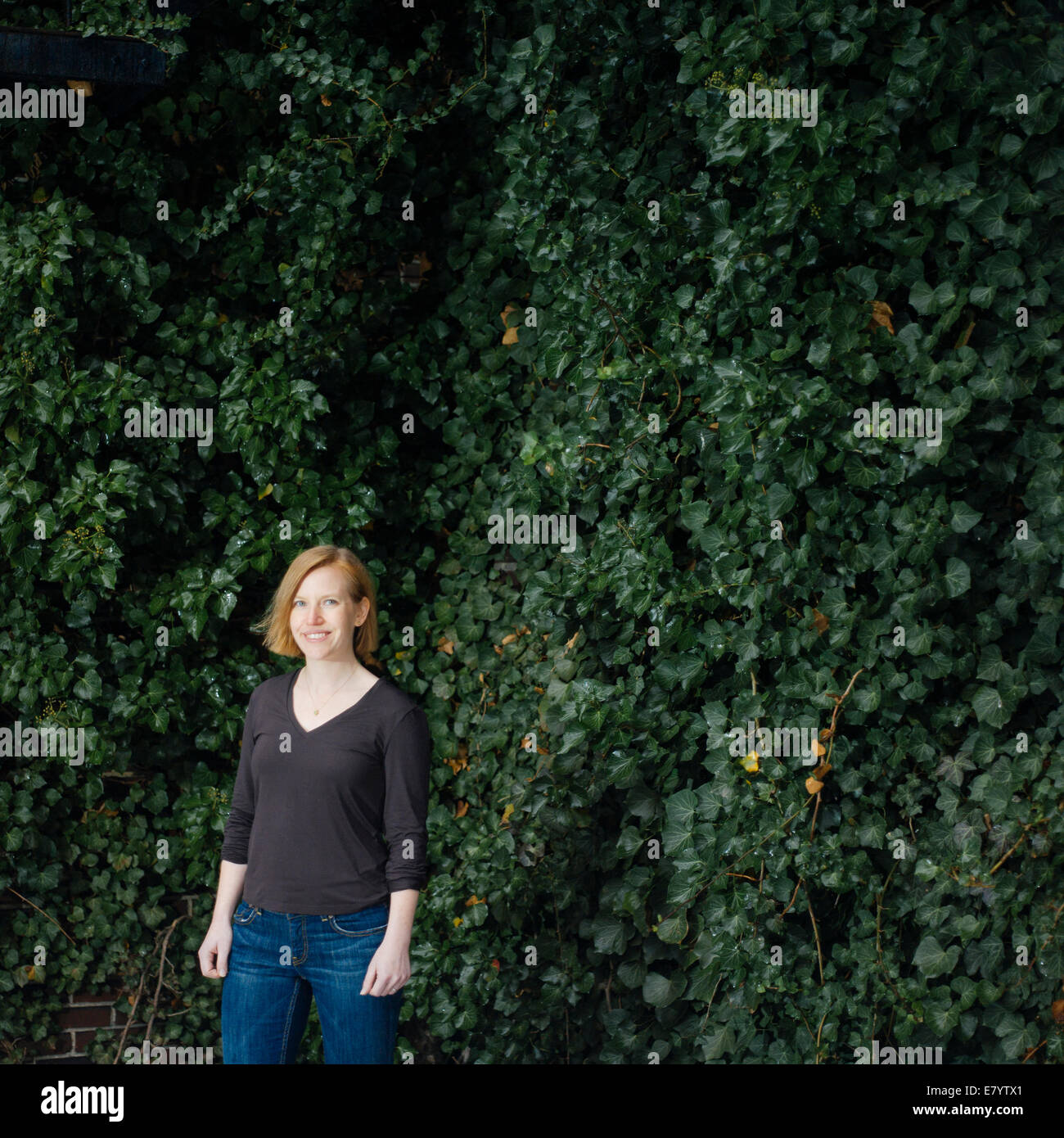 Woman standing against ivy foliage Stock Photo