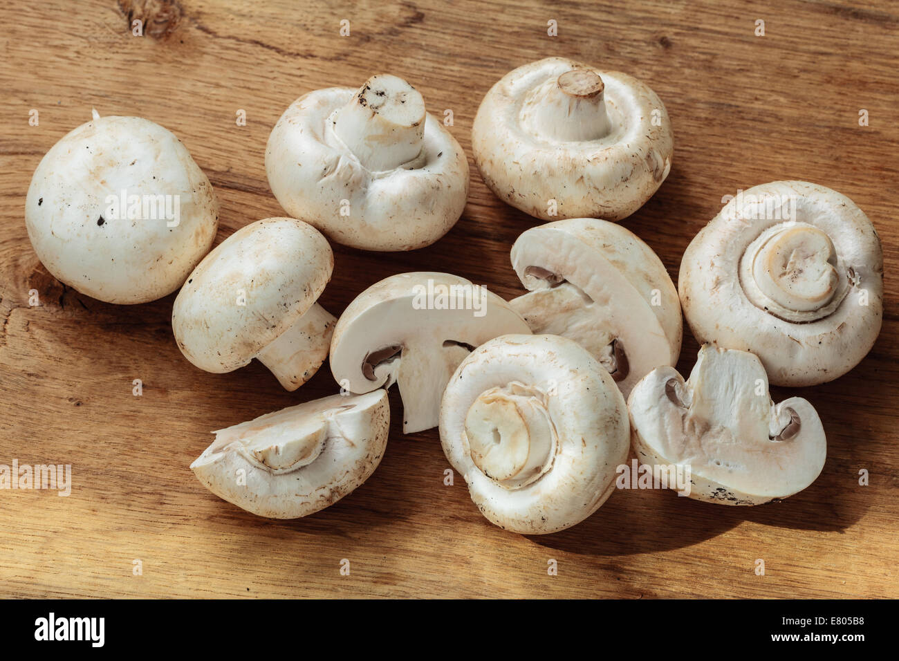 Vegetarian food. Fresh white mushrooms champigonons on wooden kitchen table. Stock Photo