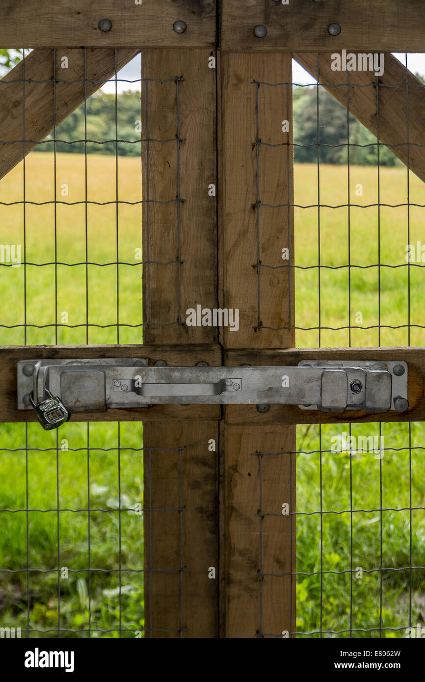 Vertical of locked wooden fence leading towards a field by the woods ...
