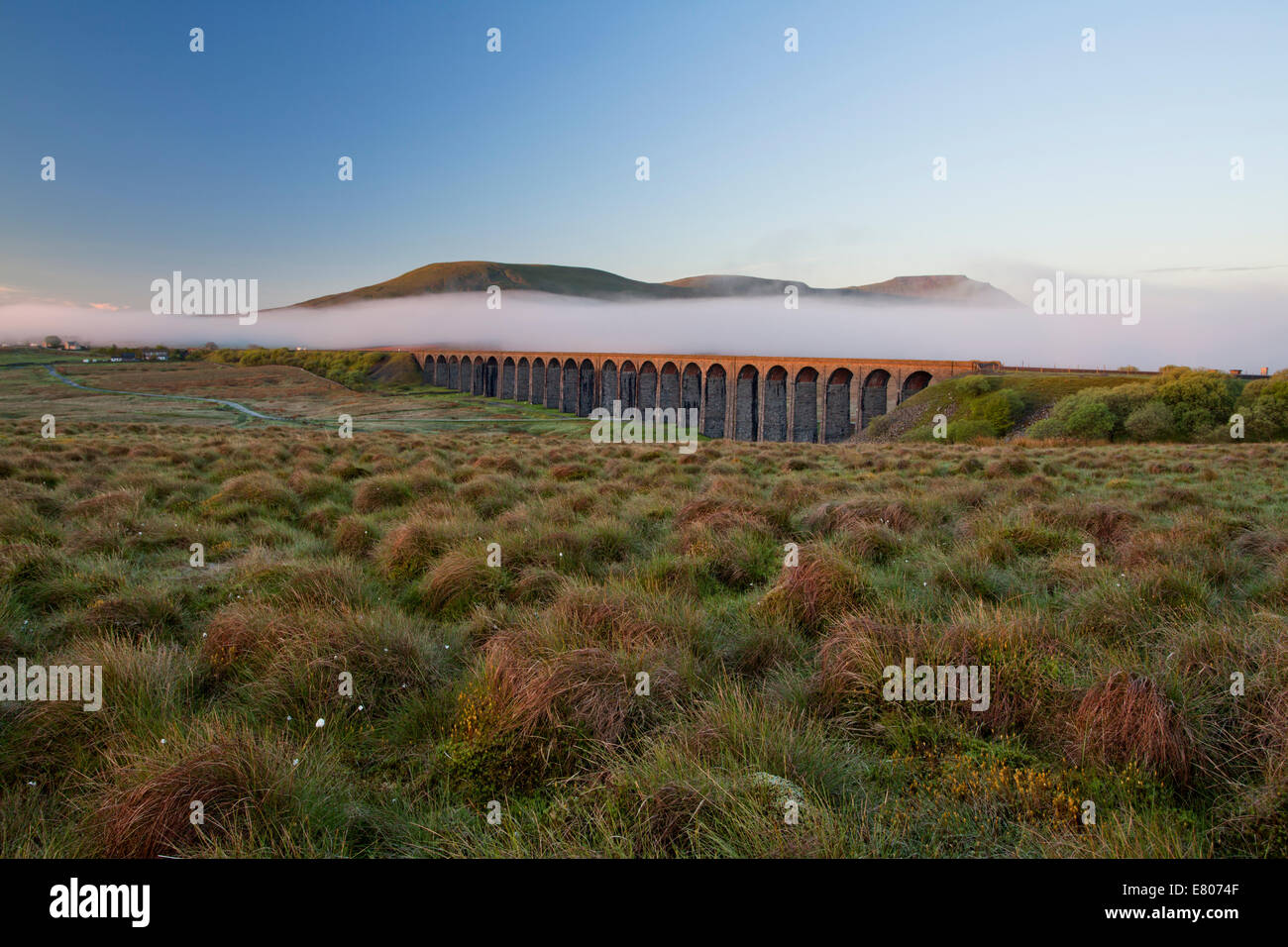 Ribblehead Viaduct in the springtime with a blanket of mist behind Stock Photo