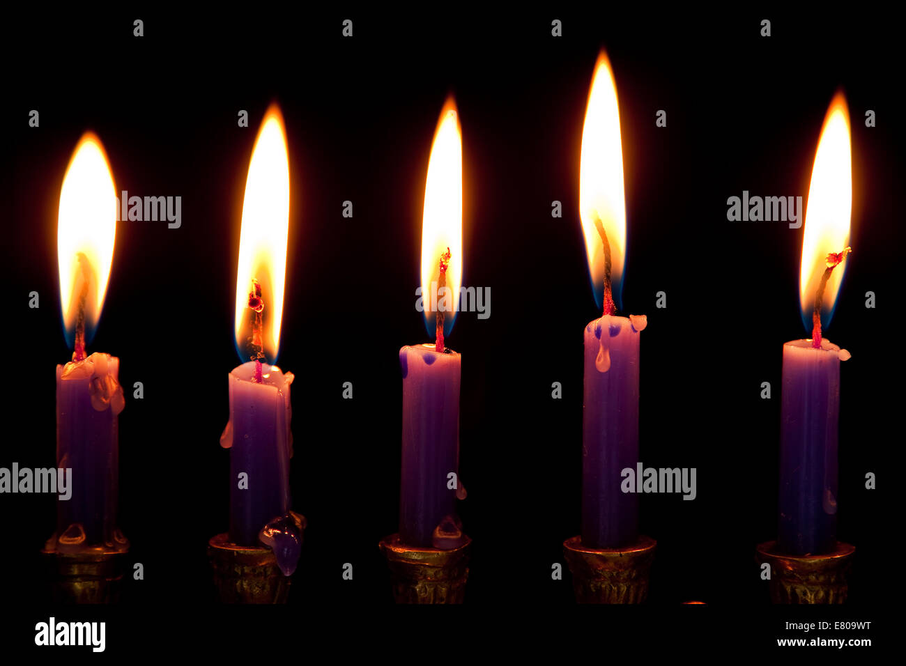 burning hanukkah candles in a menorah on black background Stock Photo