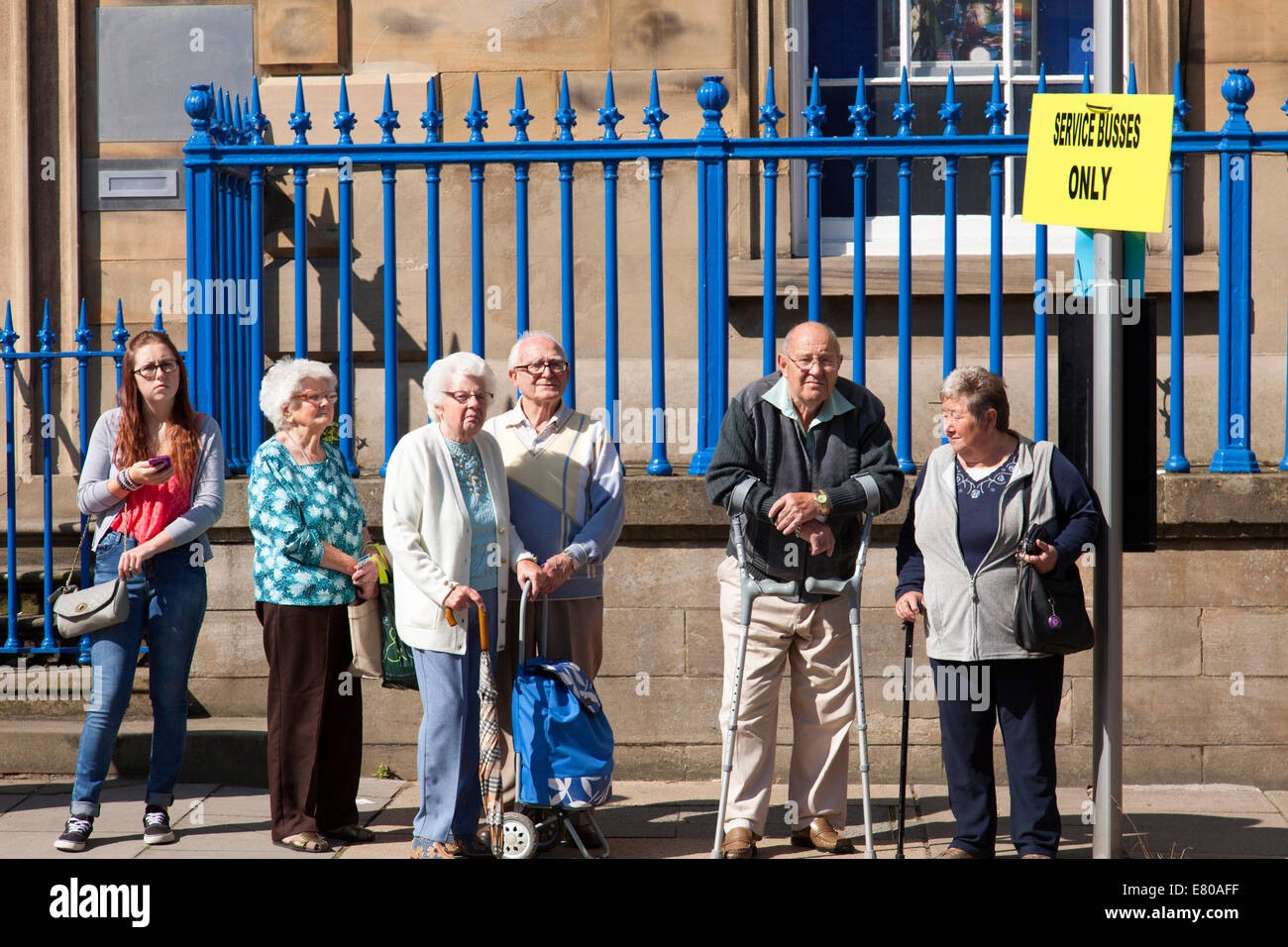Elderly passengers queuing at a bus stop in Bakewell, Derbyshire, England, U.K. Stock Photo