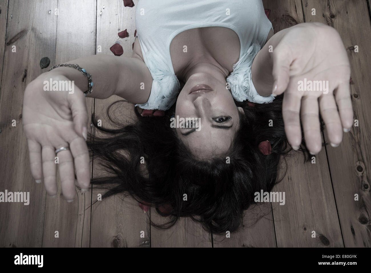 Woman lying on floorboards with her hands raised Stock Photo