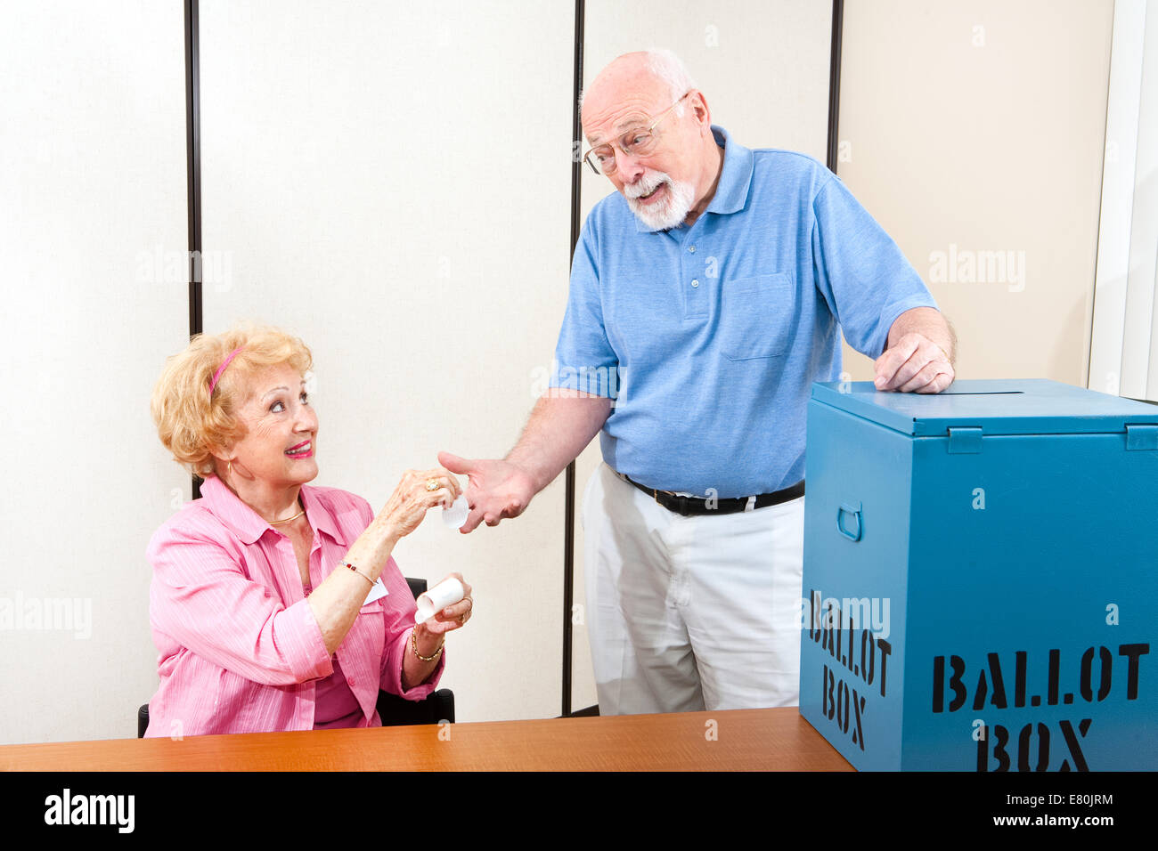 Senior poll worker giving an I Voted sticker to an elderly male voter. Stock Photo