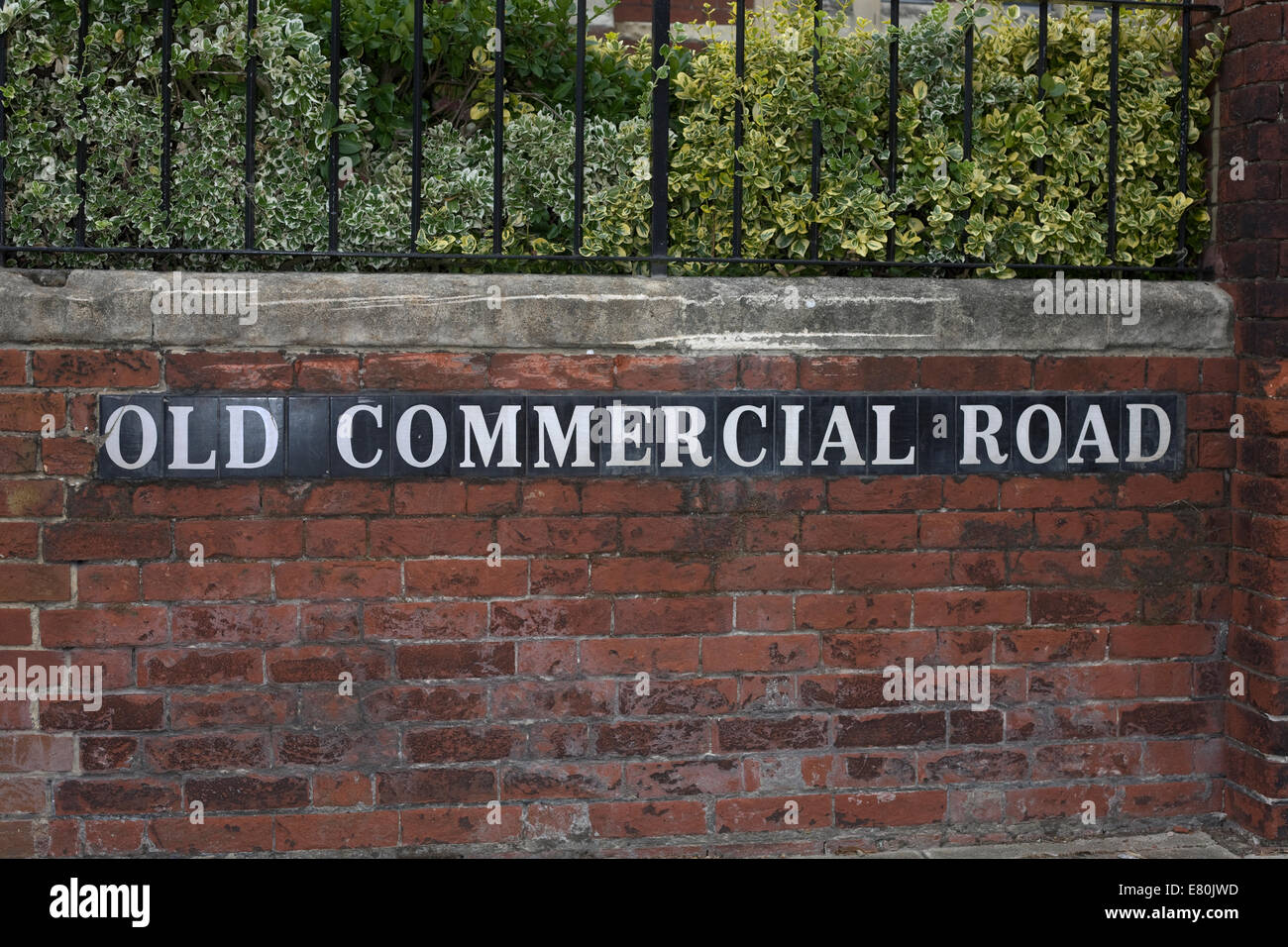 road name of Old Commercial Road set in brick wall with black metal railing above Stock Photo