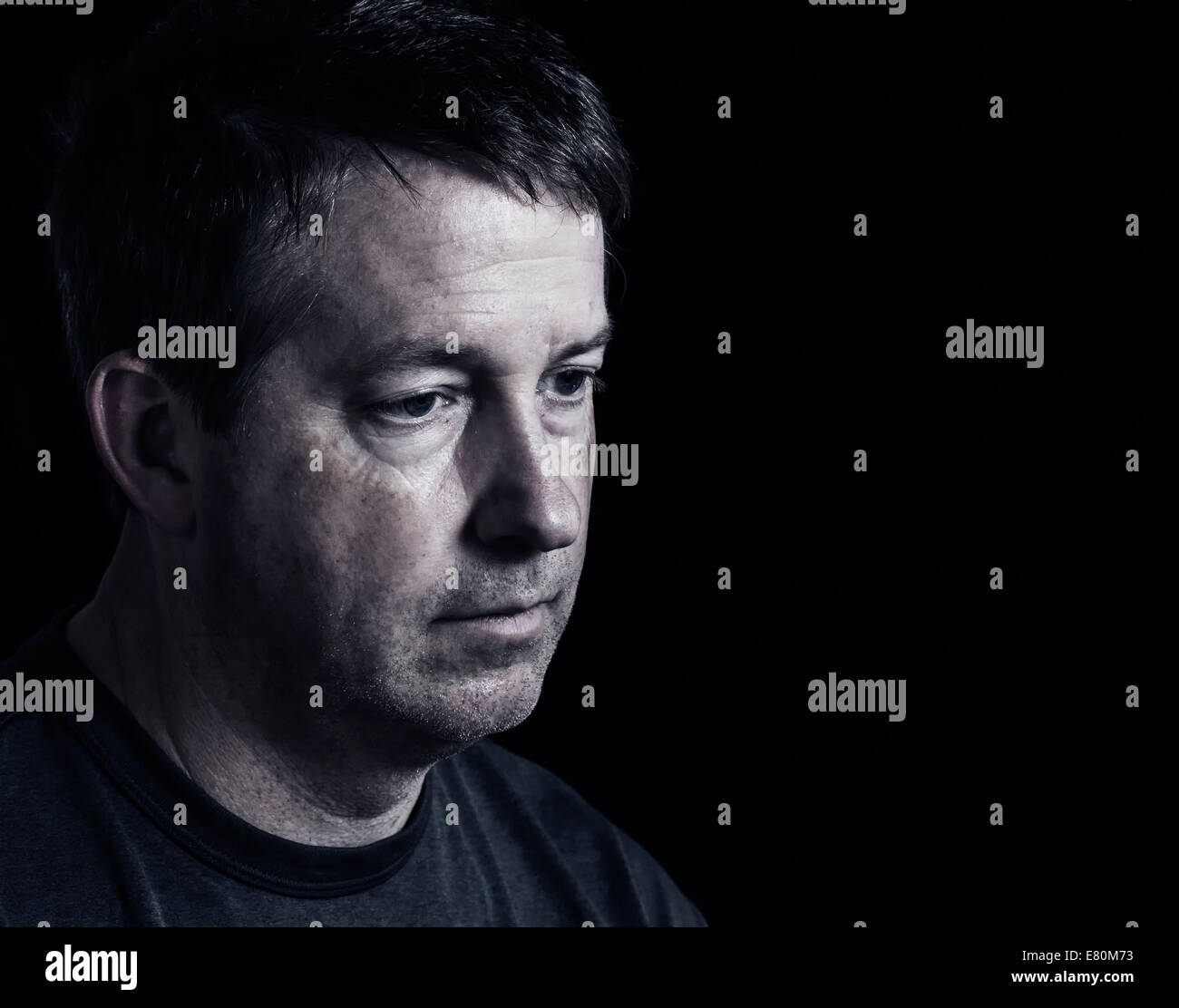 Side view close up of mature man showing negative emotions with dark background Stock Photo