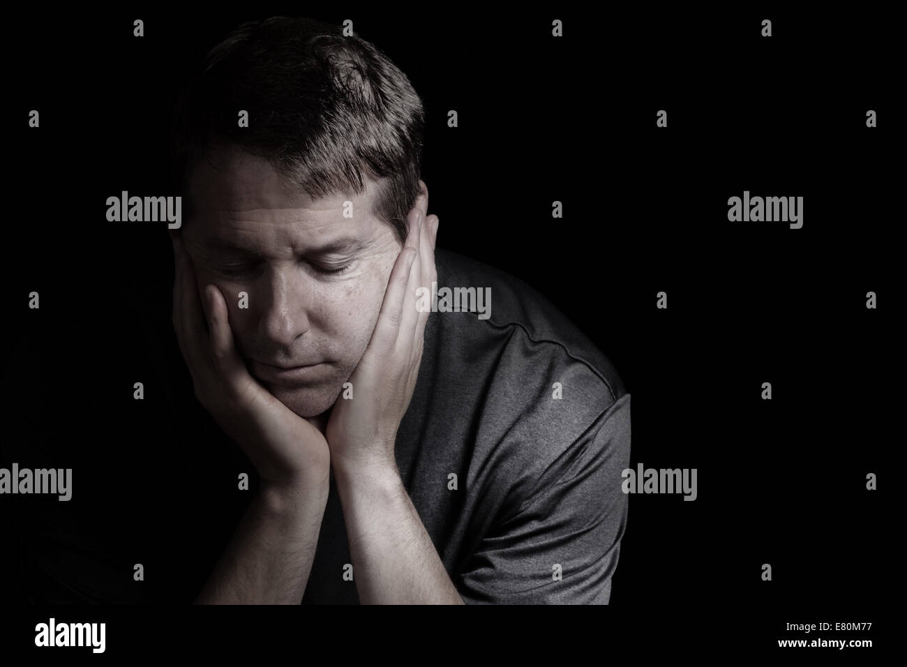 Closeup front view of mature man with head down, eyes closed and his