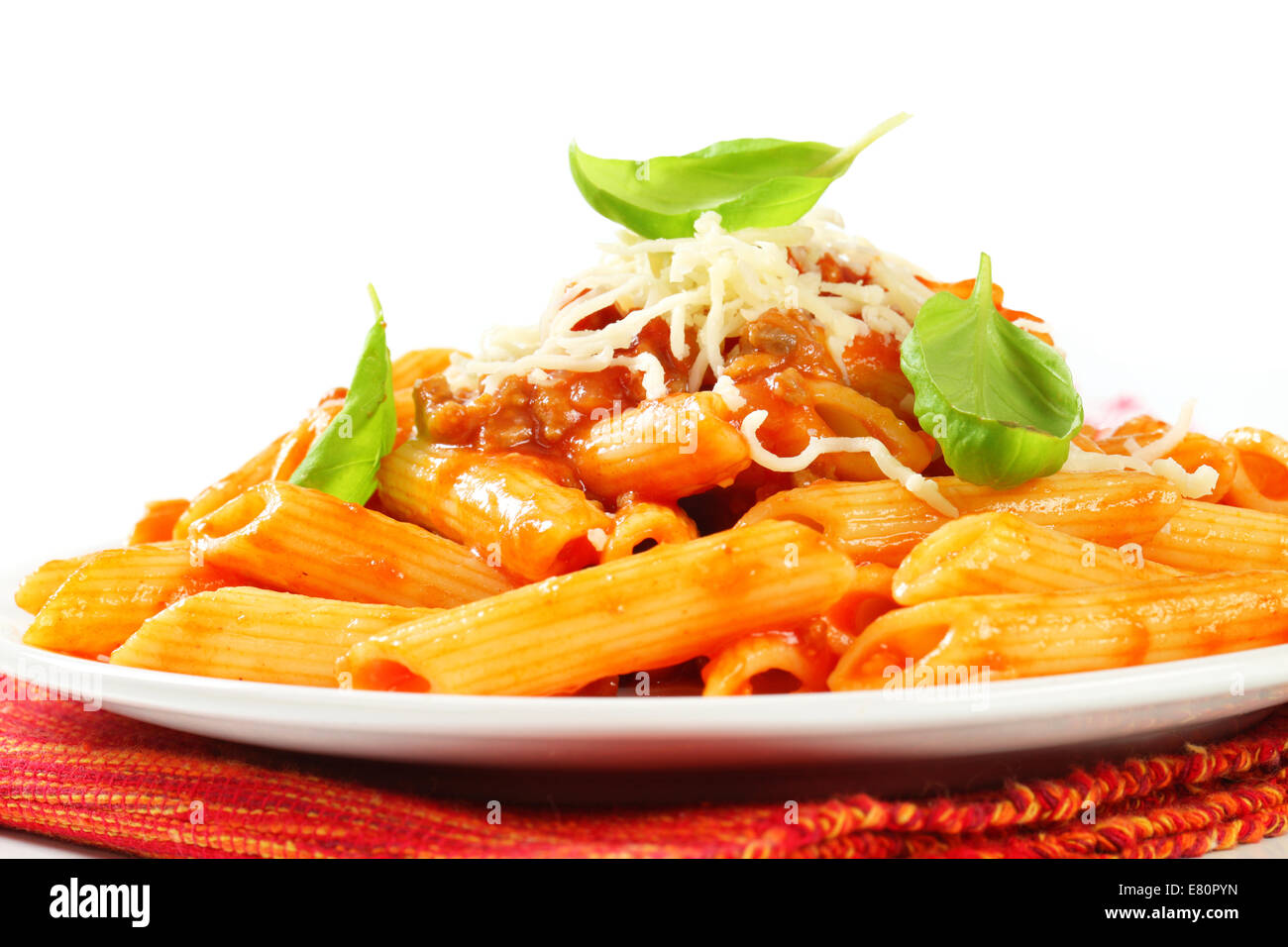 A professional plating of penne pasta coated in a rich meat-based tomato sauce, topped with melted and grated cheese.