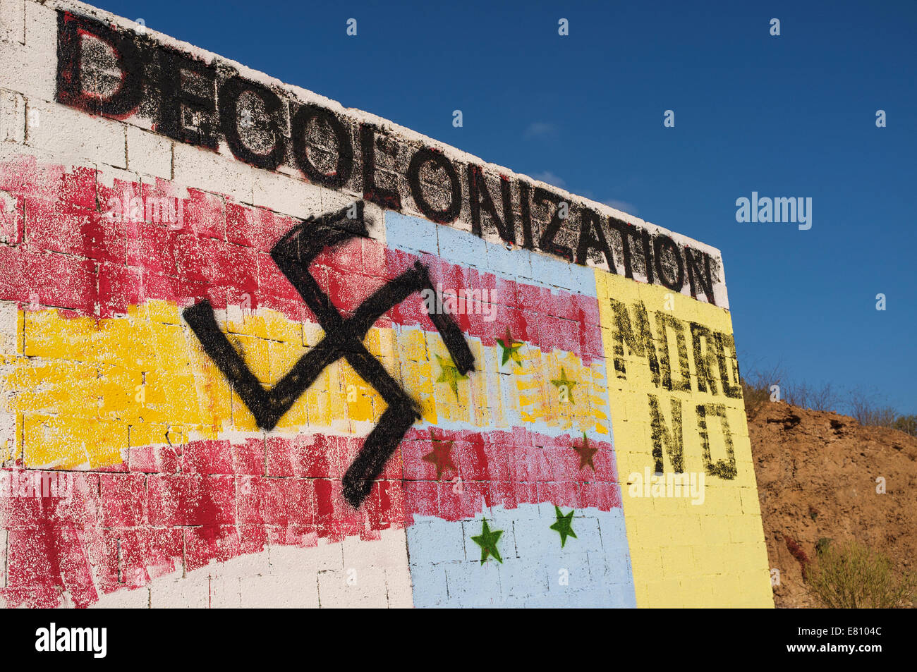 Graffiti on a wall in front of Guaza mountain, Tenerife, Canary Islands, Spain. The base is the flag of the canaries independence movement overpainted with the Spanish flag and swastika. Decolonization is a call for independence from Spain, and the Spanish flag, swastika and moro no have been added afterwards. Stock Photo