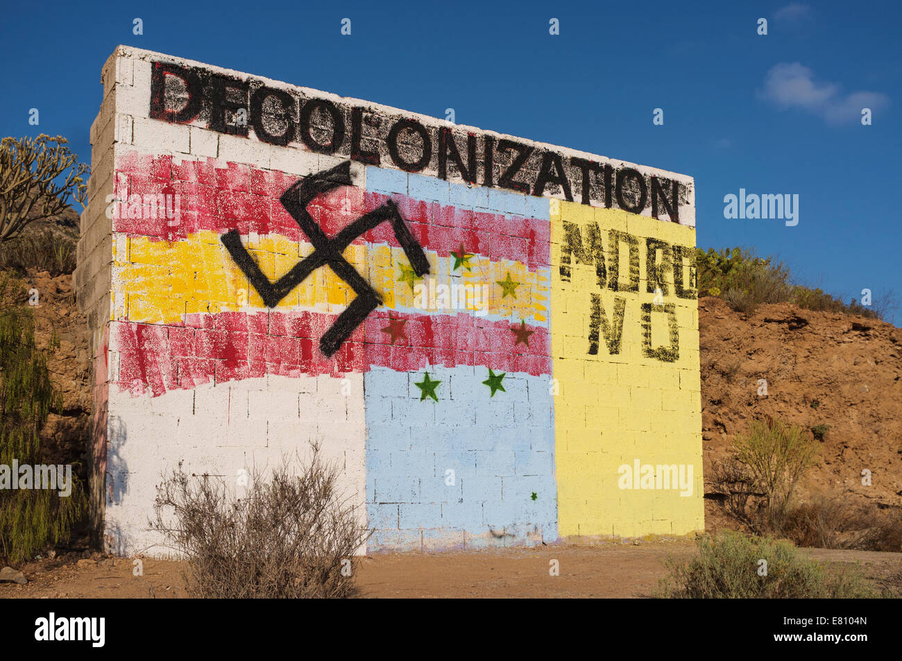 Graffiti on a wall in front of Guaza mountain, Tenerife, Canary Islands, Spain. The base is the flag of the canaries independence movement overpainted with the Spanish flag and swastika. Decolonization is a call for independence from Spain, and the Spanish flag, swastika and moro no have been added afterwards. Stock Photo