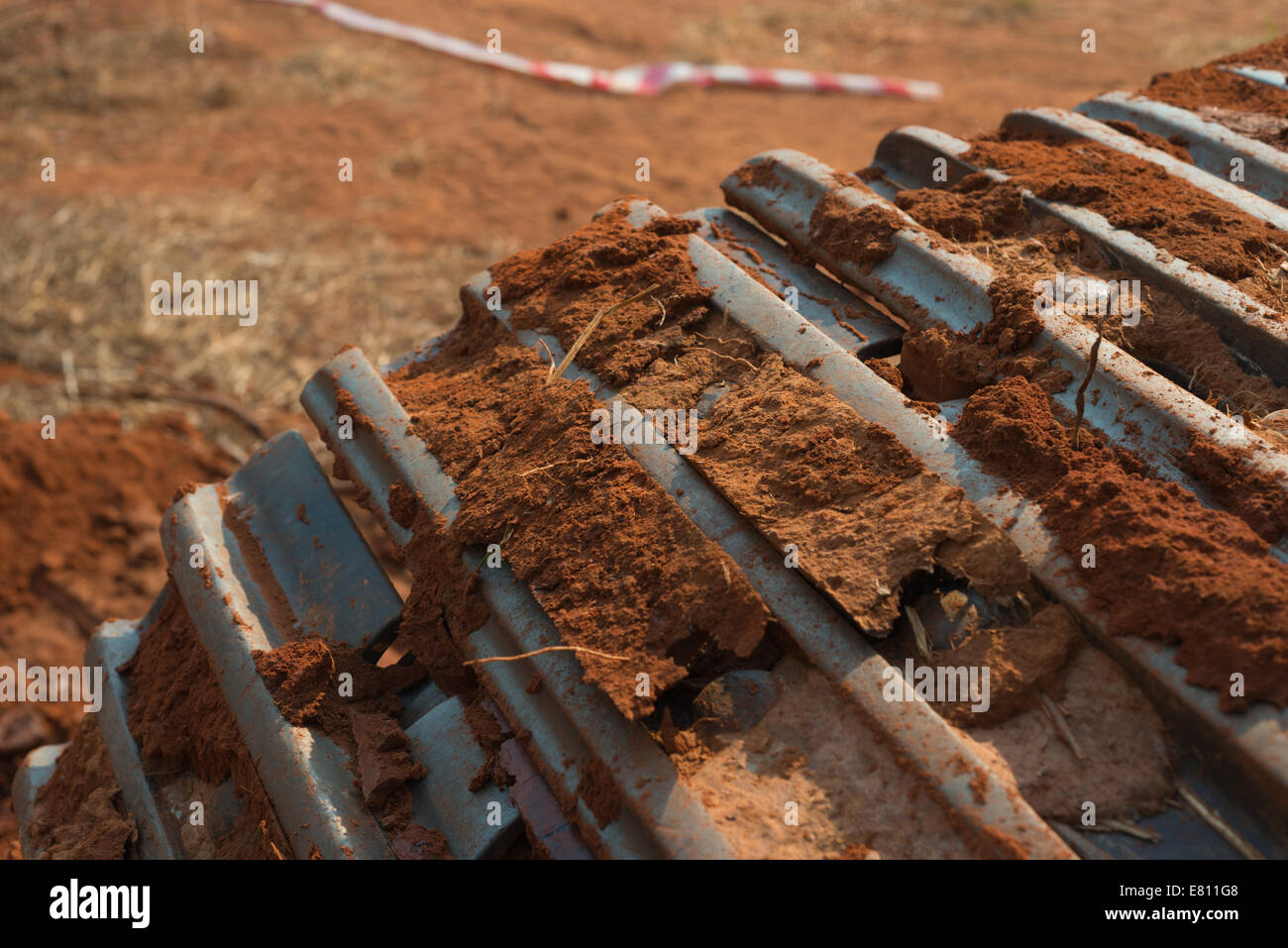 An excavator caterpillar track covered in clots of mud, dirt and laterite. Stock Photo