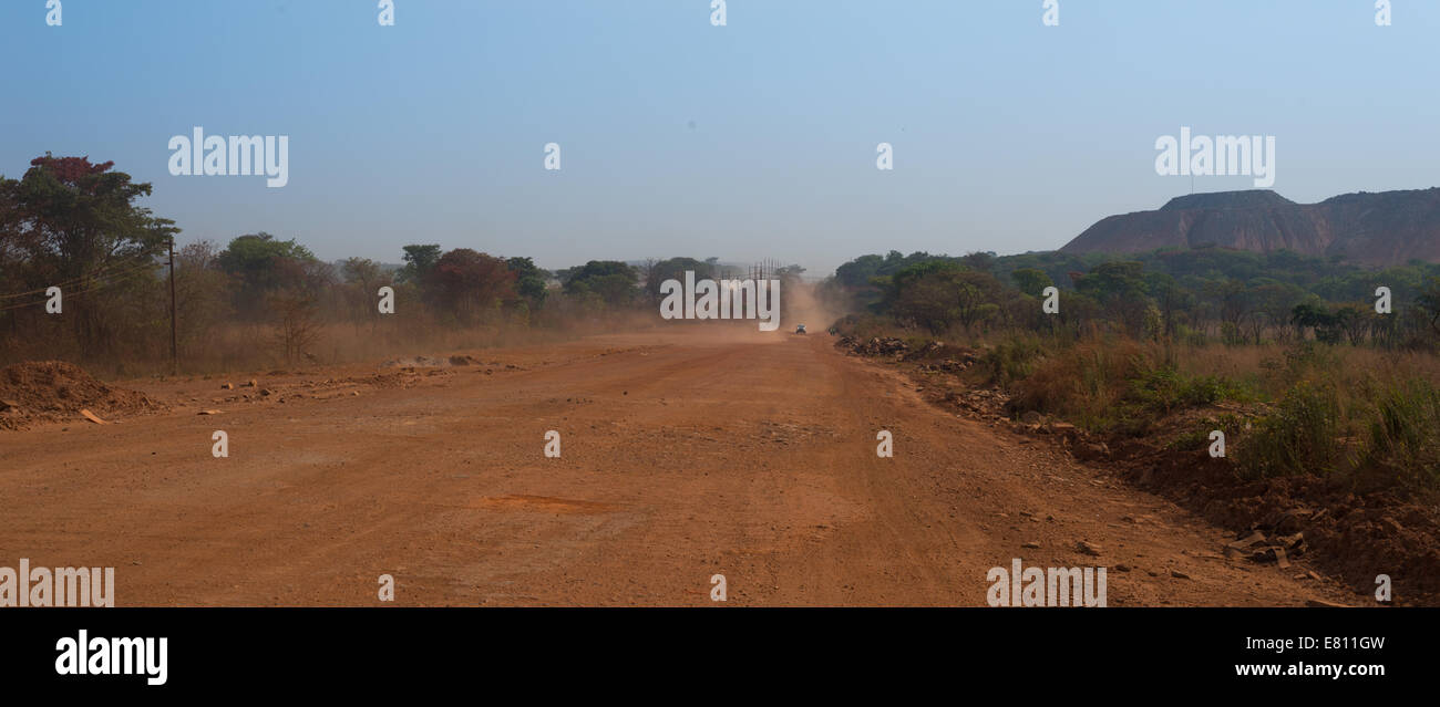 An African dirt road within a mining lease side cuts through the natural bush and dambo system. Stock Photo